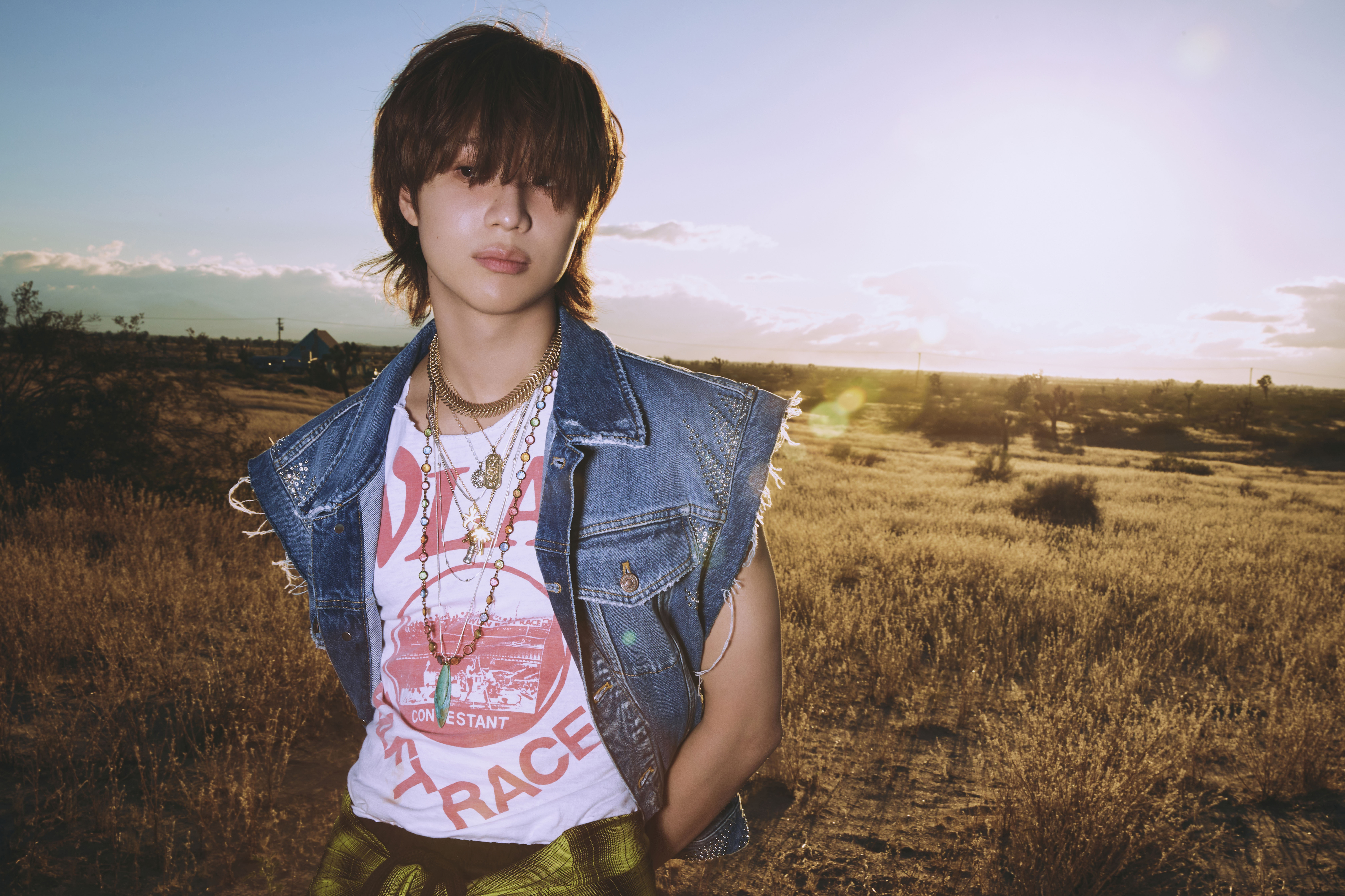 TAEMIN, exuding the raw emotions of his 'Guilty' album, stands against a golden sunset backdrop.